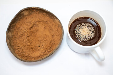 Carob powder in a bowl and a cup of hot carob cocoa.