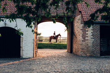 typical medieval European farm building - rider on horseback in a moment of silence in the twilight