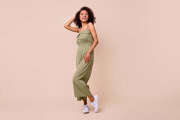 Fototapeta na wymiar Full length photo of lovely young girl touch wavy hair posing shopping promo wear stylish khaki outfit isolated on beige color background