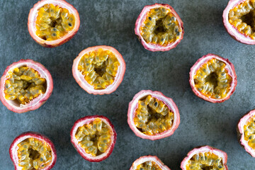 Halves of juicy sweet and sour passion fruit on a gray background. Passion fruit pattern. Exotic asian fruit background.