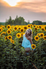 Fototapeta premium blonde girl stands in a field with sunflowers