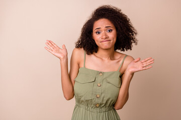 Photo portrait of pretty young lady curly hair confused shrug shoulders sorry wear trendy khaki garment isolated on beige color background