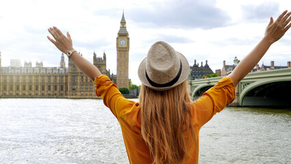 Enthusiastic traveler student girl with raised arms in London enjoying the view of mains...