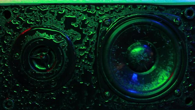 Musical speaker in water drops with beautiful colored backlight multicolored wet Musical speaker close-up