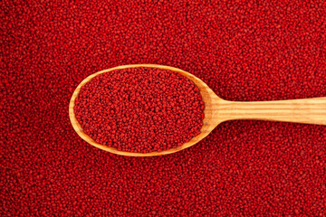 Organic Beetroot couscous in wooden spoon on of couscous background, close-up. Top view, selective focus. Design element