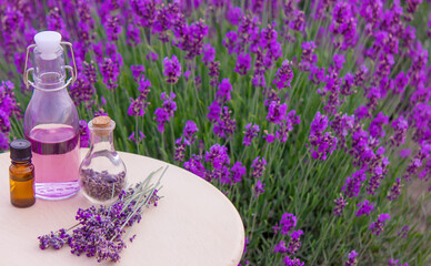 Obraz na płótnie Canvas Lavender Essential oil bottle on wood table and flowers field background