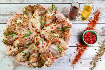 Raw chicken wings sprinkled with spices, red peppercorns and rosemary. With sauce and vegetable oil. - 520757412