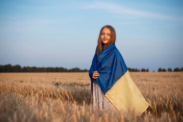Portrait of a young girl with Ukrainian flag in the field of ripe rye. Portrait of patriotic ukrainian girl