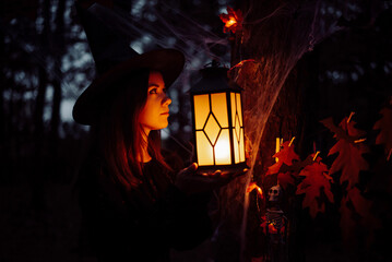 Female in night forest with burning lantern. Halloween celebration, witchcraft concept