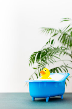 Rubber yellow duck sits in a doll bath with soap suds, soap bubbles, children's spa and hygiene concept, children's bathing accessories