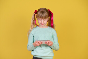 Little blond beautiful girl of 7 years , using a mobile phone