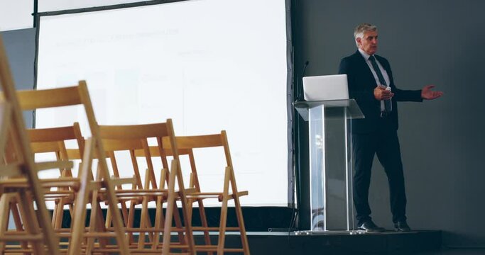 Confident businessman preparing a speech before a presentation in a conference room. A mature professional entrepreneur rehearses and practices a speech for a business seminar briefing in a room