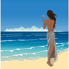 A young woman with dark hair in a silk dress on the ocean seashore with a glass in her hands