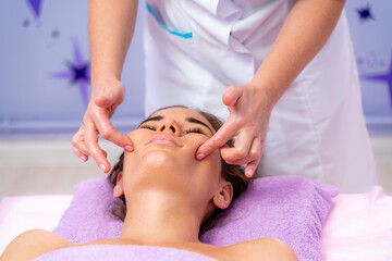 Obraz na płótnie Canvas Relaxing massage. European woman getting facial massage in spa salon, side view
