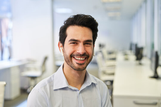 Laughing Business Man With In-ear Headphones In The Office