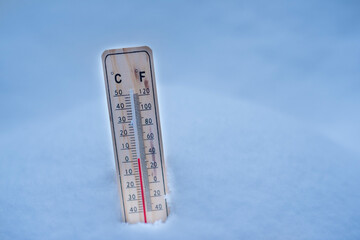 Winter time. thermometer on snow shows low temperatures in celsius or fahreneheit.