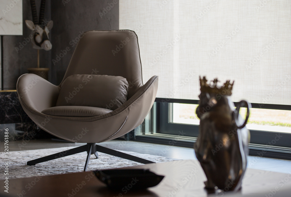 Fototapete Interior design with roller blinds in the background. Automatic solar shades of large sizes on the window. Fabric with linen texture. In front of a large window is a chair on a carpet. 