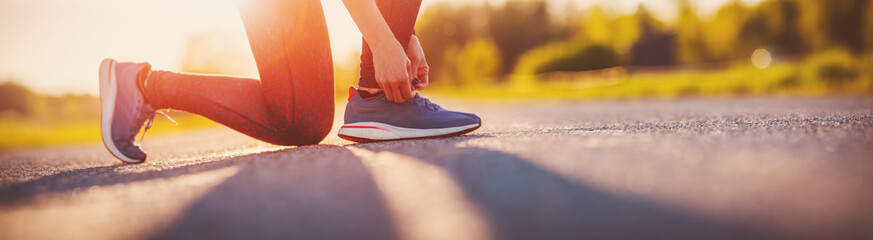 Obraz premium Sporty woman tying shoe laces before starting to run.