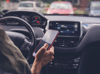 Woman looking to her smartphone while driving car in city