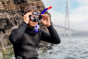 a diver in a wetsuit stands on the seashore. Diver before diving into the ocean