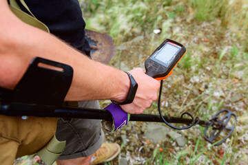 metal detector at work in the forest or field. Search for treasure and ancient values. Archeology. Man with a metal detector. Minesweeper Image. ?lose-up