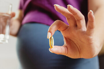 pregnant woman drinks pills. Pregnant woman holding a glass of water and vitamins for pregnant...