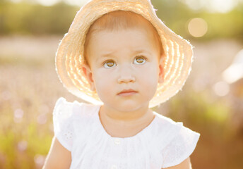 A little girl in a straw hat walking through a lavender field