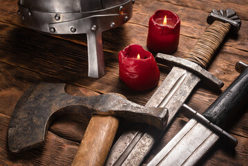 Ancient battle swords, axe and armor helmet on the wooden table background close up.