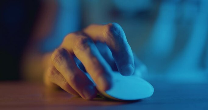 Close up of hand using wireless bluetooth computer mouse at night