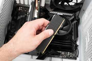 Hands of computer engineer instaliing RAM into modern desktop computer. Technology concept.