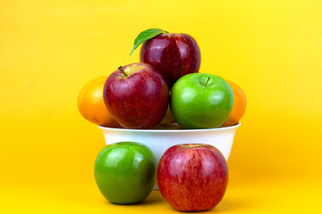 Healthy fruits, green apples, red apples, oranges isolated on yellow background. Creative composition of colorful of fruits isolated on yellow background, Close up view