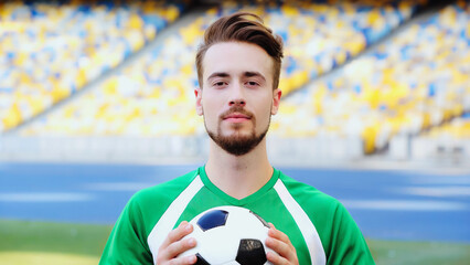 portrait of bearded and young football player holding soccer ball