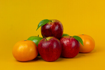 Naklejka na ściany i meble Red apple and oranges isolated on yellow background with clipping path and full depth of field for cooking concept design