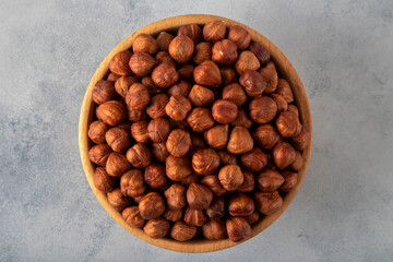 Top view of a bowl full of hazelnuts on bright background
