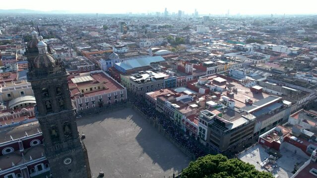 Drone video of the international women's day march walking in Puebla city streets, in the historic center near the cathedral with the whole city in the background.