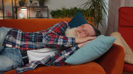 Tired one senior old man lying down in bed taking a rest at home. Carefree elderly mature grandfather napping, falling asleep on comfortable sofa with pillows. Closed her eyes enjoy daytime nap alone