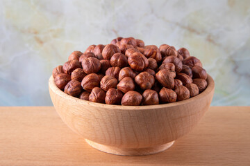 Bowl full of hazelnuts on wooden background
