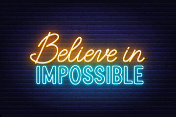 Fototapeta na wymiar Believe in impossible neon quote on a brick wall.