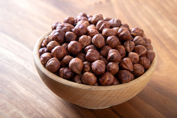 Bowl full of hazelnuts on wooden background
