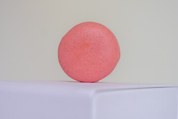 Close-up of appetizing pink macaroon on white box on light background.