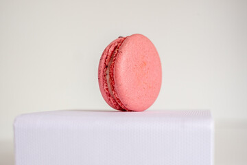 Close-up of appetizing pink macaroon on white box on light background.