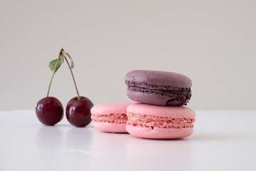 Appetizing colorful macarons with cherries on white background.