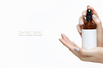 Beautiful manicured female hands holding up an atomiser bottle with blank white label. Cosmetology and skincare mockup isolated on white