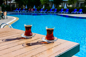 Black tea in traditional turkish glasses on table near the swimming pool