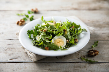 Healthy arugula salad with egg and walnut