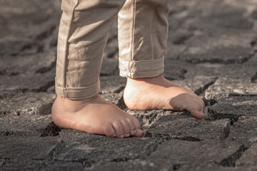 Bare children's feet on the cobblestones. The child is barefoot. Children's bare feet. Walk without shoes. Go forward. Freedom to be yourself.