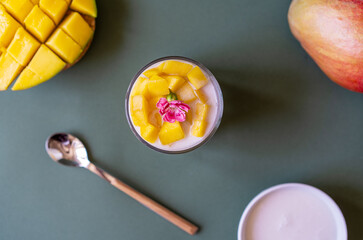 Thai mango dessert with sticky rice and coconut milk decorated by carnation. Cut and whole mangos,...