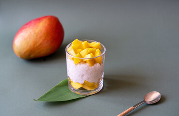 Thai dessert with mango and sticky rice and coconut milk decorated by carnation, sugarcane leaf,...