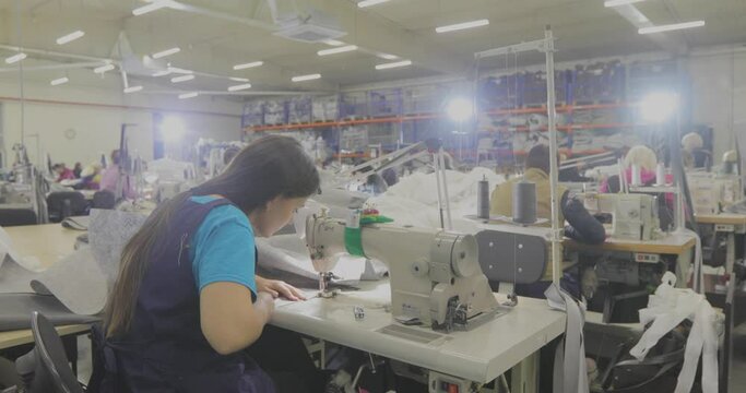 A woman works in a garment factory. A woman works on a sewing machine. Making textiles in a factory