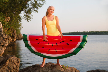 Summer lifestyle portrait senior woman in swimwear with air mattress looks like watermelon on the...